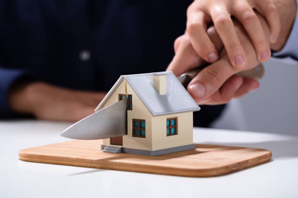 divorced couple cutting a mini house through the middle with a knife