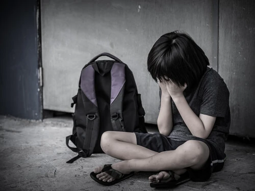 Sad Kid sitting on the floor with school bag